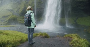 Women with backpack in front of epic Seljalandsfoss waterfall Iceland