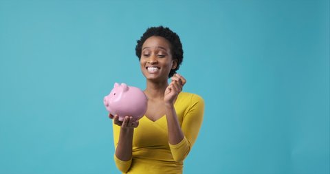 Woman inserting coin into piggy bank