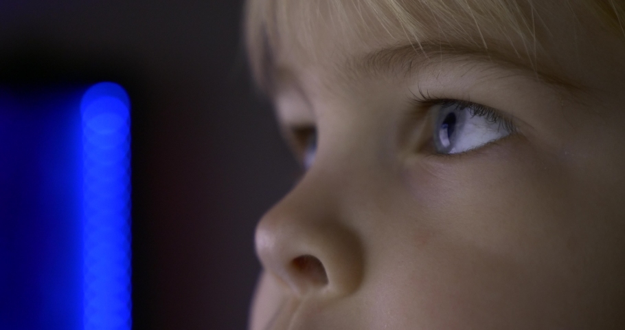 Close-up Child Blue Eyes. Reflection Computer Monitor TV Screen. Natural Candid Reaction Emotions. Boy Watches Action Video Movie
