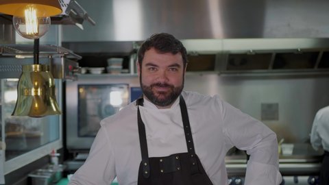 Smiling male Chef cook portrait in restaurant's commercial industry kitchen zoom out 