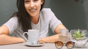 Medium 4k video of a young, beautiful, Latin Hispanic woman drinking coffee in garden cafe or home patio. 