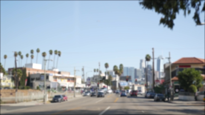 Driving on downtown streets of Los Angeles, California USA. Defocused view from car thru glass windshield on driveway. Blurred road with vehicles in Hollywood. Camera inside auto, LA city aesthetic.