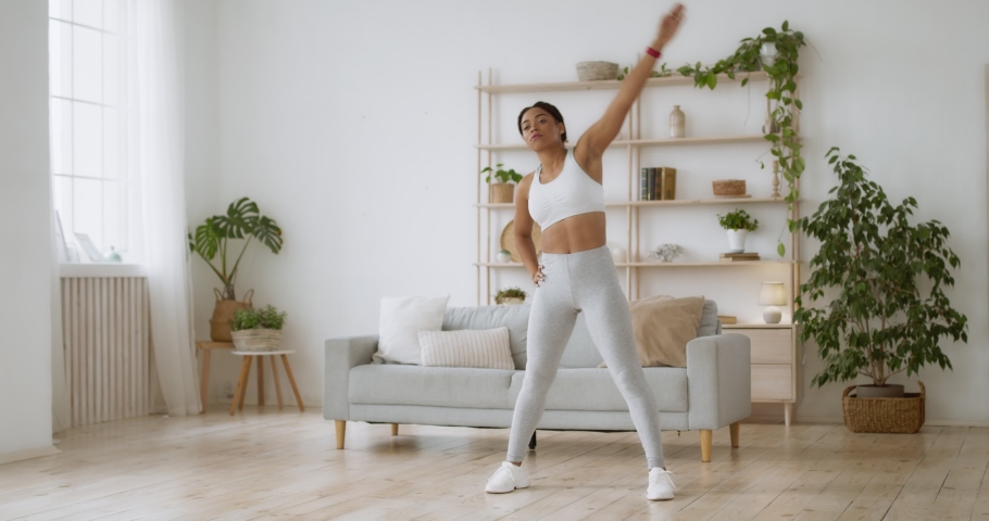 Body stretching activity. Young sporty african american lady tilting to both sides at home, full length, slow motion Royalty-Free Stock Footage #1062165217