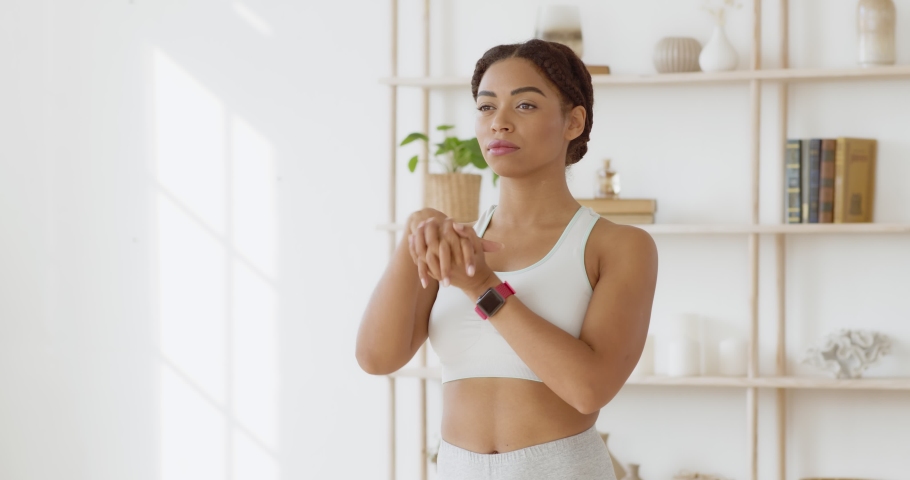 Safety sports training. Young black sporty lady warming up her wrists before strength workout at home, slow motion Royalty-Free Stock Footage #1062165223