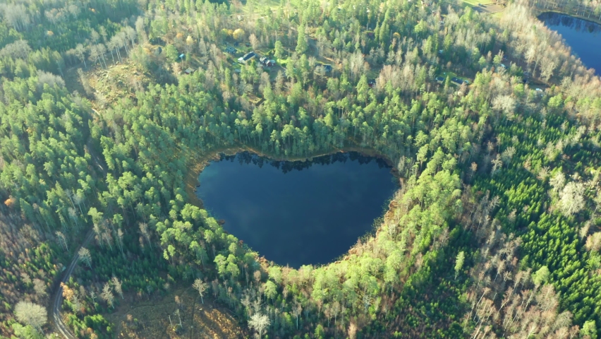 Heart shaped lake in forest. Tilting drone shot of natural wonder in nature environment. Symbol sign for love peace save the our planet in Swedish woods. blue pond water with special shape in Sweden.  Royalty-Free Stock Footage #1062167665