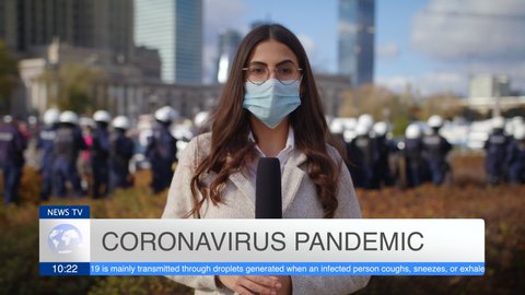 Caucasian Young Woman Journalist In Protective Mask Presenting Breaking News TV About Coronavirus Pandemic On Street Outdoors Lot Of People Police In Background Pandemic City Protest And March Slow Mo