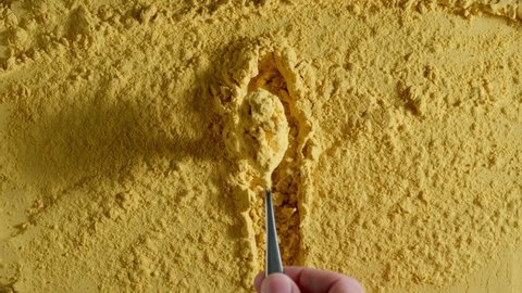 TOP VIEW: Yellow turmeric powder is taken by a spoon