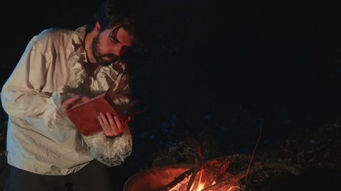 Poet reading by a fire outside