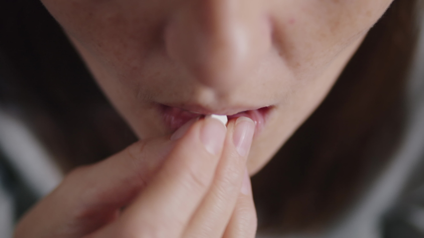 close up of a woman taking a white zinc pill and drinking water