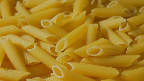 Lots of penne pasta close-up rotates top view. Production of pasta. 4k
