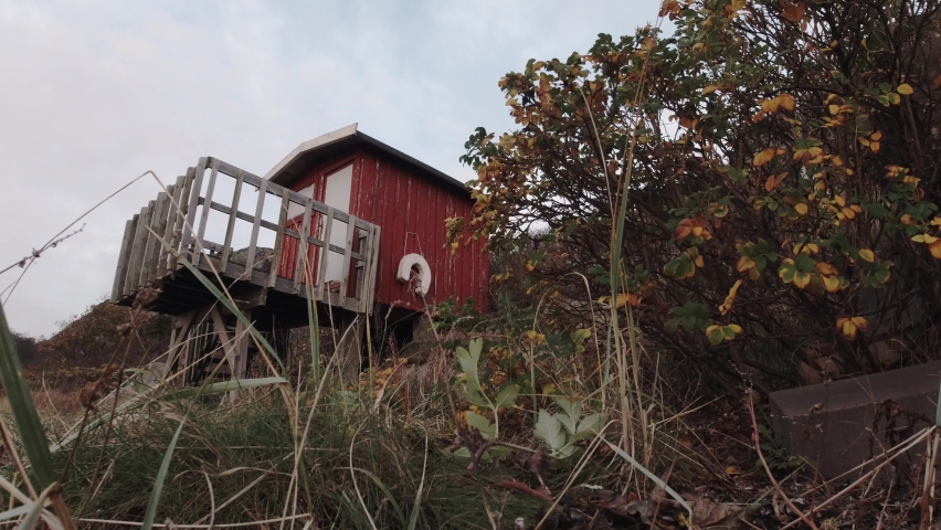 Seaside holiday hut one windy evening in Hovås, Sweden. Red bathing cabin on the beach. 4K footage, tripod ground view.