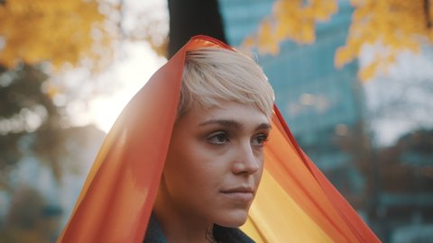 beutiful young woman with short hair lifing rainbow flag from her head in the air. High quality 4k footage