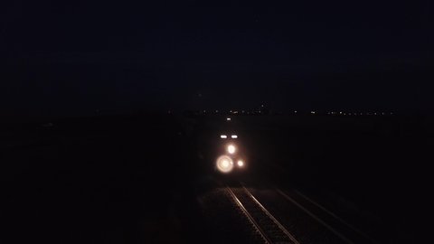 Freight train lights prairie railroad tracks on dark purple night