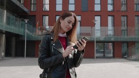A young woman surfing the Internet on smartphone flipping good new and smilling of the business center background. Shot in motion from the steadicam 4k