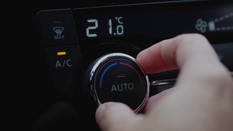 set up air conditioner in the car. Hand turns air conditioner ring. Display indicates temperature inside the car. Cooling air in the car