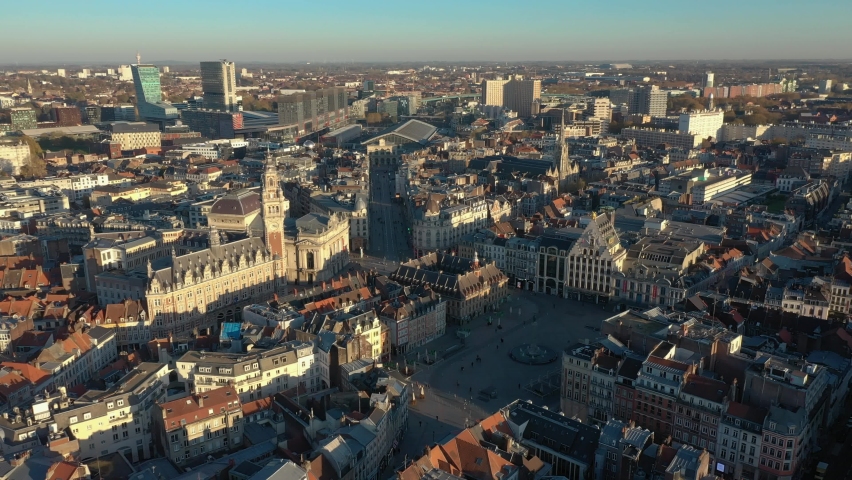 France, North, Lille, left to right drone aerial view above the Général De Gaulle Grand-Place during sunset (or sunrise), belfry of the chamber of commerce and train station in the background | Shutterstock HD Video #1062196642