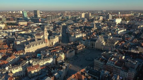 France, North, Lille, left to right drone aerial view above the Général De Gaulle Grand-Place during sunset (or sunrise), belfry of the chamber of commerce and train station in the background