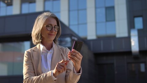 Positive business woman in elegant suit smiling scrolling web pages smartphone