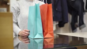 Unrecognizable young woman passing shopping bags to client at cash desk in store. Caucasian female shop assistant serving customer in shopping center or mall. Trading and service concept. - Powered by Shutterstock - Get 15% off with code: PIKWIZARD15