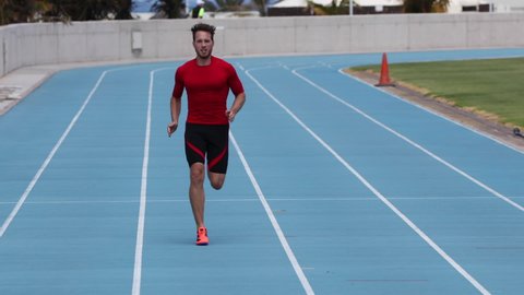 Running sprinter man in sprint training on athletics track and field stadium fast at high speed. Male athlete runner in intense sprint exercise. Run sport concept.