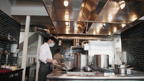 Chefs in protective masks and gloves prepare food in the kitchen of a restaurant or hotel, high kitchen during coronavirus covid 19 pandemic, business reopen after quarantine. - Powered by Shutterstock - Get 15% off with code: PIKWIZARD15