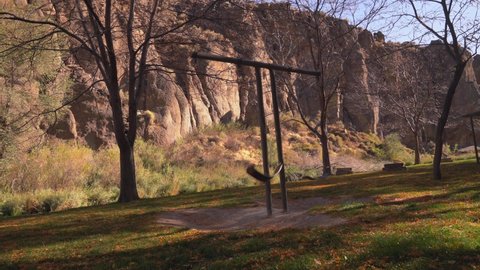 This video shows swings swinging on an empty playground with an epic canyon background behind.