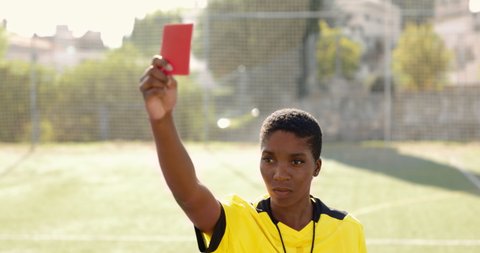 African-american female referee blowing whistle and holding red card