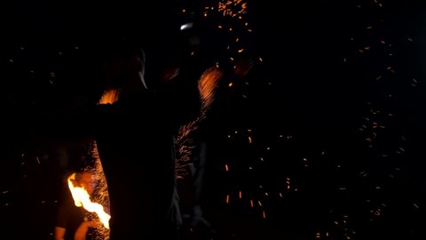 A lot of burning sparks fly in different directions. The man is breathing a flame. Fire escapes from the mouth. Performance of fire show artists in an abandoned place. Slow motion. 4K