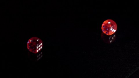 Slow movement of rolling game cubes on the black table.Rolling red casino dice