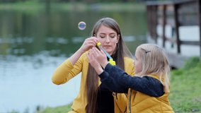 Mother and daughter inflate soap bubbles. Family portrait in backlight. autumn park, spend time together. Family time. close up Shot video. Slow motion footage