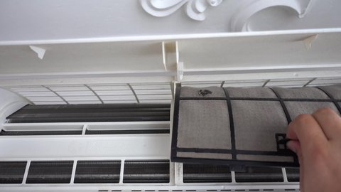 Removing the dust filters on the air conditioner for washing and cleaning. Concept for maintenance of hygiene and pure air to prevent allergies and breathing problems.. Air conditioner net being taken