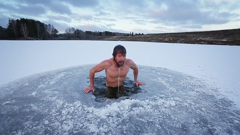 Winter swim. Young man with beard swims in a winter lake. Scene 1, camera 1