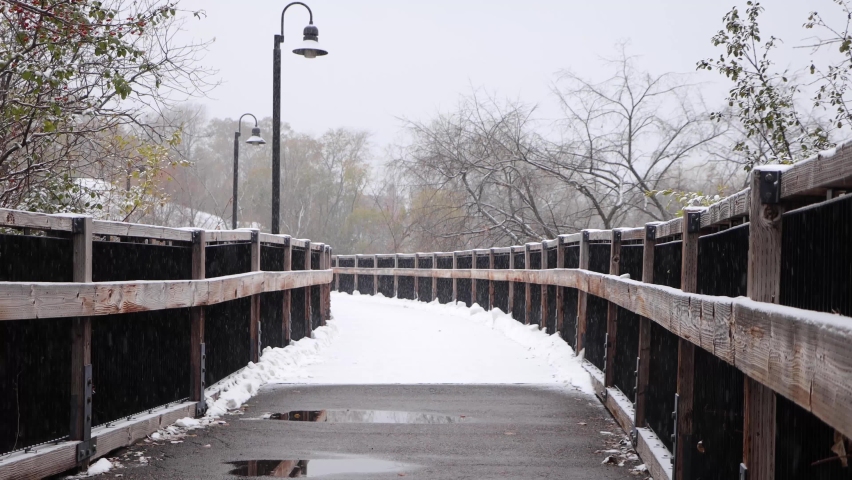 Snow covered old wooden bridge during fresh snowfall. Static. Chippewa River State Trail, Wisconsin.