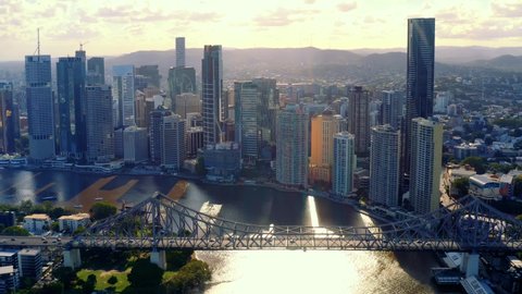Vehicles Driving Across Story Bridge Over Sparkling Water Of Brisbane River At Sunset - Luxury Hotels And High Rise Buildings At Brisbane, Queensland, Australia. - aerial