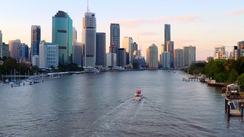 Motorboat Sailing At Brisbane River Overlooking The High-rise Buildings At Brisbane CBD At Sunset In QLD, Australia. - aerial