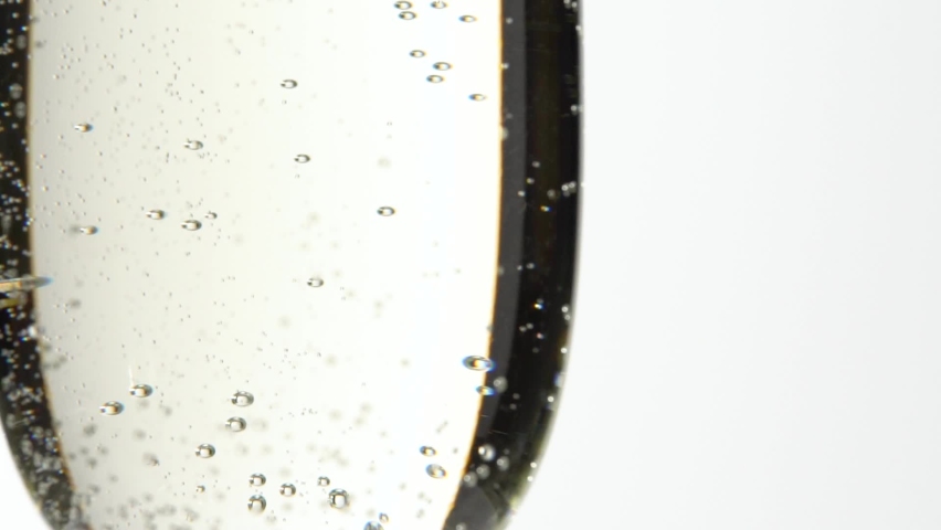 Jet Of Champagne Of Carbonated Drink Or An Alcoholic Cocktail Is Poured Into Glass On A White Background. Concept Of Tasting Alcoholic And Non-alcoholic Beverages In Cafes Bars And Restaurants