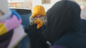 bokeh shot of warmly dressed people students crowd at street in winter  . defocused children and young woman stand near car. blurred citizens outdoor in cold on the sidewalk