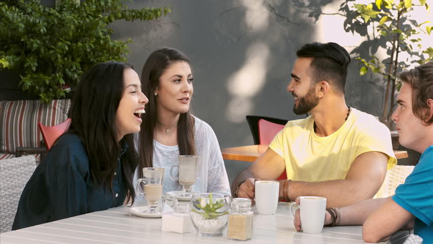 4k medium video multicultural group of young friends chatting and laughing together in a small garden cafe or home patio garden. 