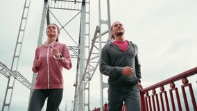 Low angle view of happy runners running and giving high five on bridge