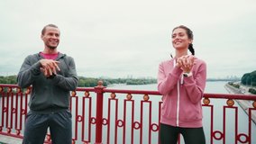 Front view of smiling couple in sportswear warming up with nature on background