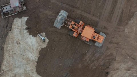 Bulldozer works on construction site with sand, aerial or top view. Top Aerial view on Tracked Bulldozer Rides on Sandy Road at Construction Site
