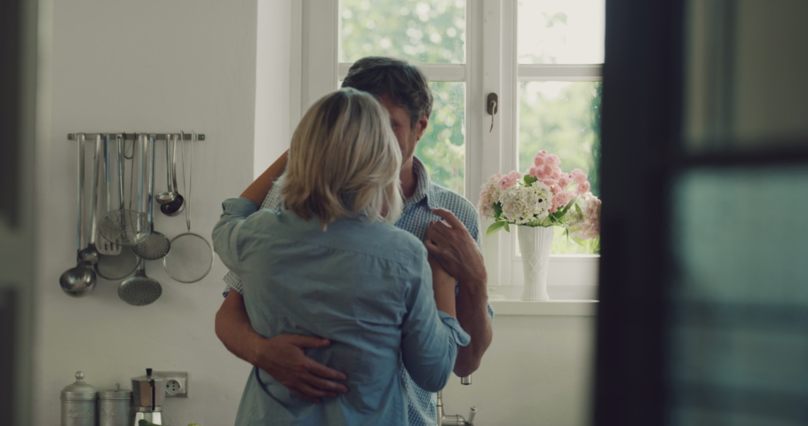 Cinematic shot of lovely happy mature couple is having fun dancing to celebrate their timeless love in a kitchen at home.  Royalty-Free Stock Footage #1062230479