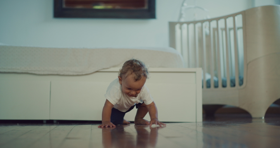 Cinematic shot of a cute happy little toddler baby boy is crawling on a wooden floor at home. Concept: life, childhood, authenticity, parenthood, home Royalty-Free Stock Footage #1062231646