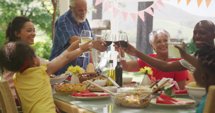 Multi-generation African American family spending time in garden together, sitting at a dinner table, making a toast, in slow motion. | Shutterstock HD Video #1062233149