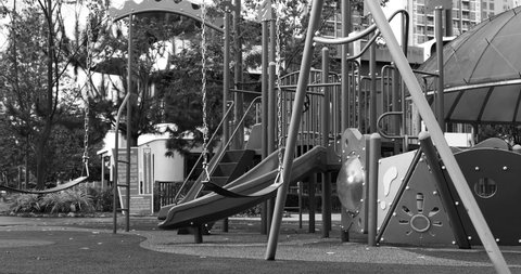 Kuala Lumpur, Malaysia - November 8, 2020: A slow motion footage of an empty, abandoned, slowly swinging swing in a playground
Black and white shot to highlight the sadness of the scene