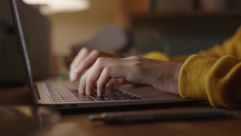 Hand of woman using laptop computer to work, typing at home, while sitting on table workplace at night, Close-up of young women hand
