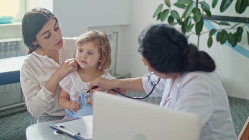 Female Doctor Pediatrician Using Stethoscope Listen to the Heart of Happy Healthy Cute Kid Girl at Medical Visit With Mother in the Hospital. Female Doctor Examining Child. | Shutterstock HD Video #1062235921