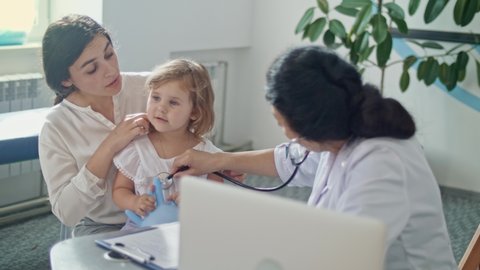 Female Doctor Pediatrician Using Stethoscope Listen to the Heart of Happy Healthy Cute Kid Girl at Medical Visit With Mother in the Hospital. Female Doctor Examining Child.