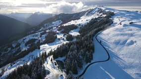 Drone flying over the mountains in a landscape with lots of snow and trees