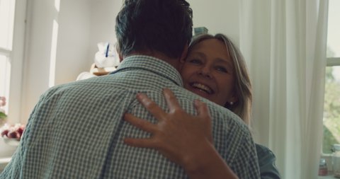 Cinematic shot of lovely happy mature couple is enjoying time together and and having fun dancing to celebrate their timeless love in a kitchen at home. Concept: love, family, marriage, home